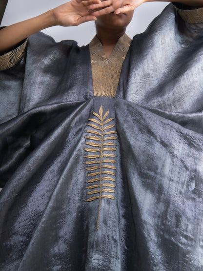 Gray fabric with gold leaf embroidery held by a person against a neutral background