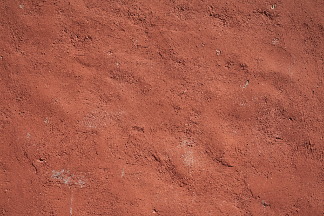 A plain textured red wall clicked in daytime